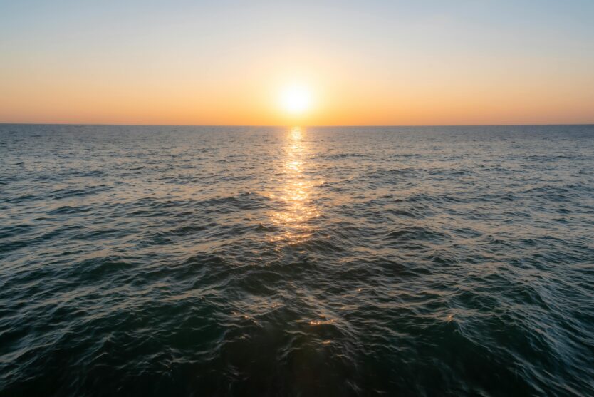 Beautiful sunset over the ocean with golden reflections on the water's surface, creating a serene seascape.